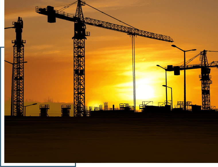 A sunset with cranes in the background and traffic lights.